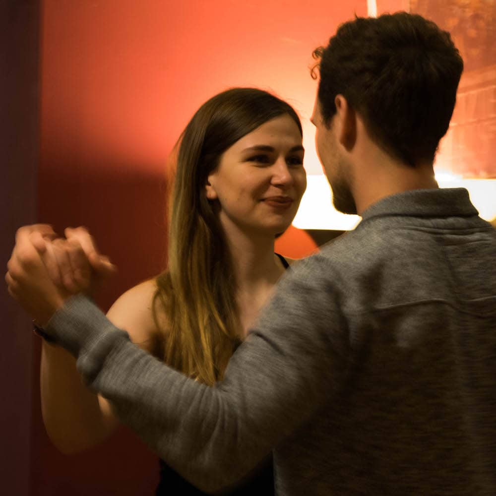 Eine junge Tangotänzerin schaut ihren Tanzpartner beim Tanzen lächelnd an